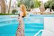 A woman in a long dress standing by a swimming pool.