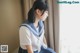 A woman in a school uniform sitting on a window sill.