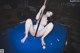 A woman sitting on top of a pool table holding a cue.