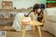 A woman sitting on the floor with a cake on a table.