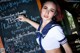 A woman in a school uniform writing on a blackboard.