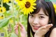 A young woman holding a sunflower in front of her face.