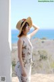 A woman wearing a straw hat standing next to a wall.