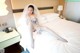 A woman in a wedding dress sitting on a bed.