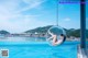 A woman laying in a hanging chair by a swimming pool.